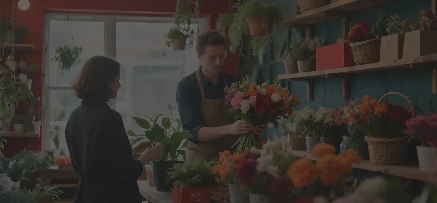 Mulher sendo atendida em uma floricultura pelo dono do pequeno negócio que necessita marketing e comunicación